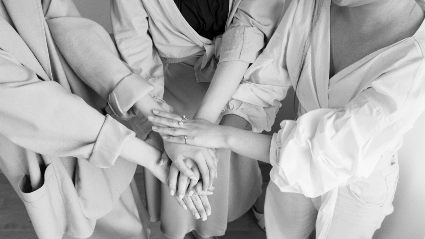 a group of women putting their hands together, a black and white photo, aestheticism, wearing white silk robe, 15081959 21121991 01012000 4k, wearing elegant casual clothes, instagram post