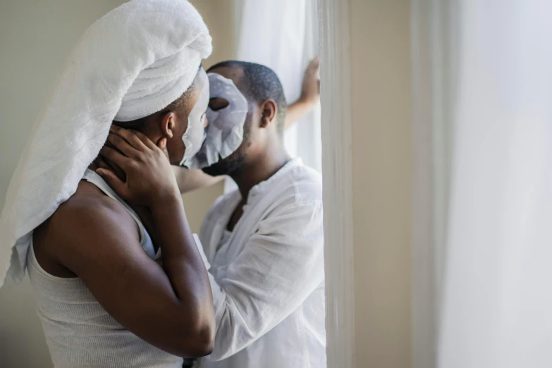 a man and woman kissing in front of a window, by Arabella Rankin, pexels contest winner, wearing a white bathing cap, african mask, skincare, couple on bed