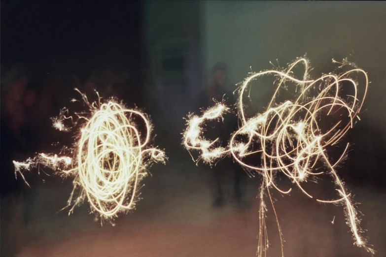 a couple of sparklers sitting on top of a table, by Cerith Wyn Evans, process art, lomography photo, medium format. soft light, close - up photograph, electric swirls