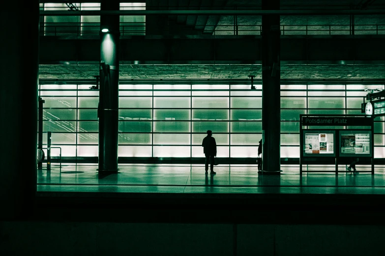 a person standing in front of a large window, inspired by Andreas Gursky, unsplash contest winner, postminimalism, train station, green glows, silhouette of a man, instagram post