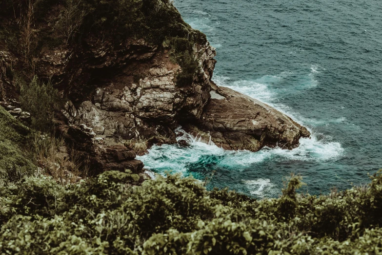 a person standing on top of a cliff next to the ocean, by Daniel Lieske, pexels contest winner, visual art, dense thickets on each side, manly, covered with vegetation, visable sounds waves