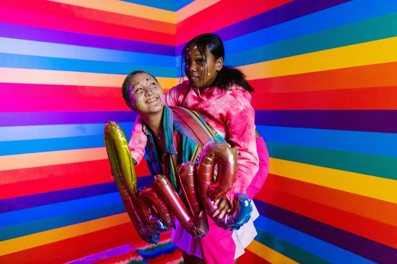 a man and woman standing in front of a colorful wall, a portrait, pexels, interactive art, rainbow tubing, willow smith young, cardboard cutout of tentacles, colorful uniforms