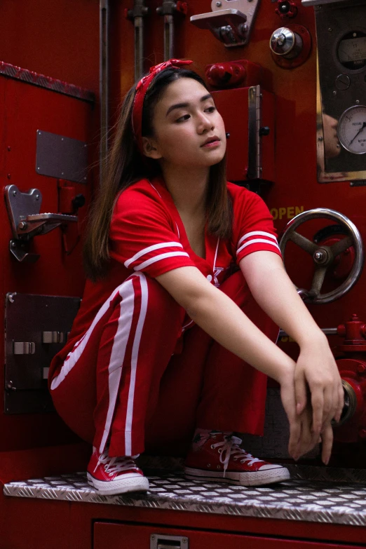 a woman sitting on top of a fire truck, inspired by Pia Fries, pexels contest winner, wearing a track suit, cindy avelino, red uniform, dilraba dilmurat