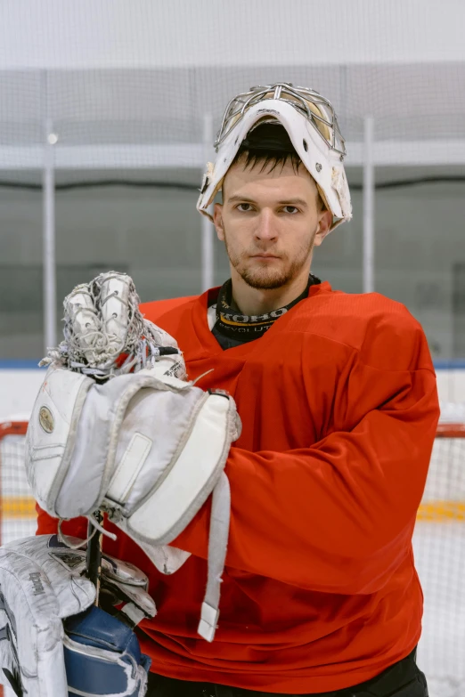 a man standing in front of a goalie net, a portrait, reddit, red gloves, official photo, shiny silver, danila tkachenko