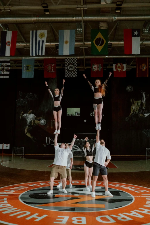 a group of people standing on top of a basketball court, acrobatic moveset, orange grey white, jets, high ceiling