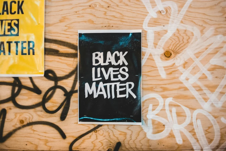 a sign that says black lives matter on the side of a building, a cartoon, pexels contest winner, black arts movement, on a coffee table, risograph poster, background image, sticker - art