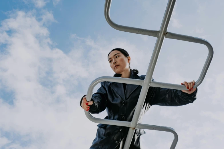 a woman standing on top of a metal ladder, pexels contest winner, wearing leather coat, blue skies, maggie cheung, avatar image