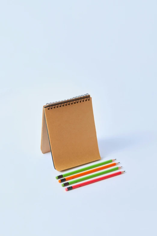 a notepad sitting on top of a pile of colored pencils, by David Simpson, 3/4 front view, fan favorite, small, raw sienna