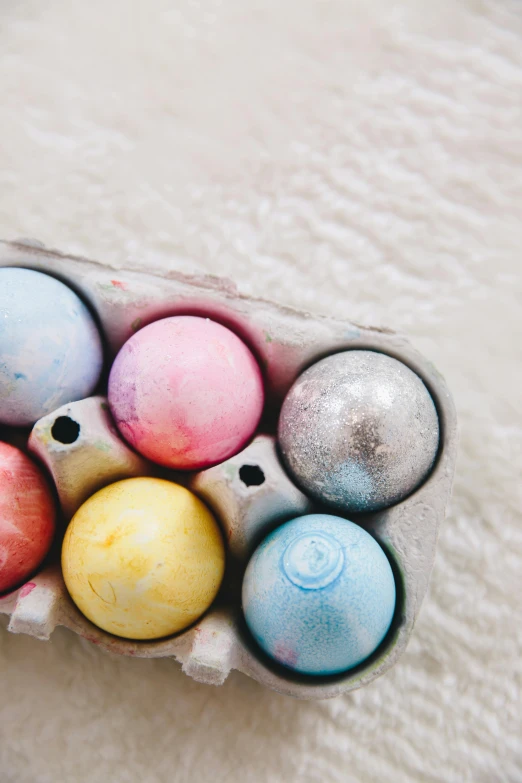 a carton filled with lots of different colored eggs, by Sylvia Wishart, trending on unsplash, ilustration, ornaments, chalk, rainbow sheen