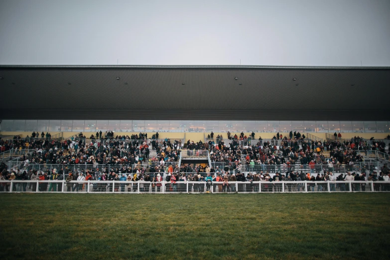 a crowd of people watching a horse race, inspired by Andreas Gursky, pexels contest winner, grey sky, square, pavilion, football