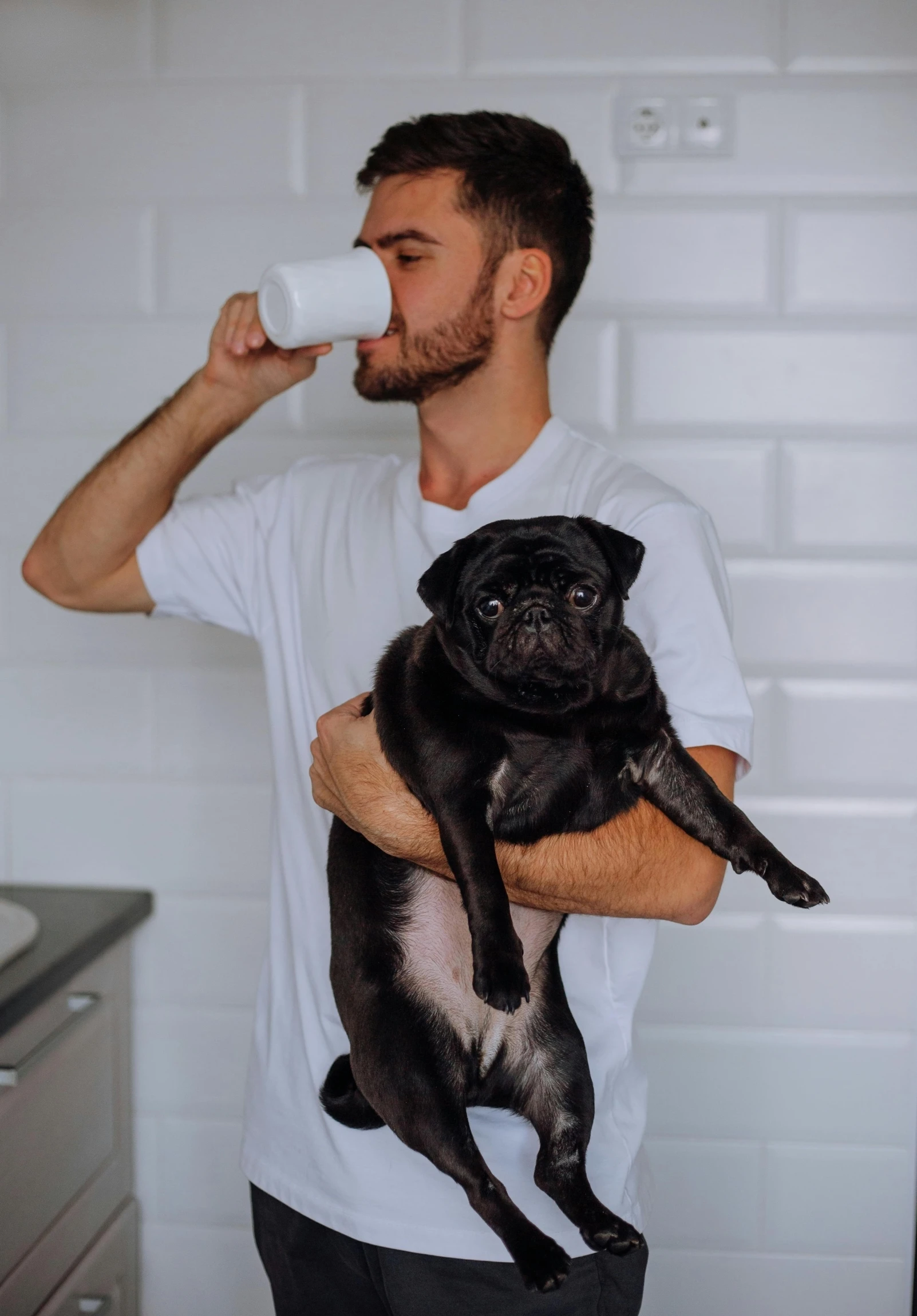 a man drinking from a cup while holding a dog, profile image, aussie baristas, leaked photo, holding a pug for a picture