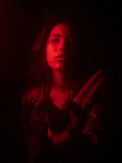 a woman standing in front of a red light, inspired by Elsa Bleda, soft devil queen madison beer, crawling out of a dark room, gesture, profile image