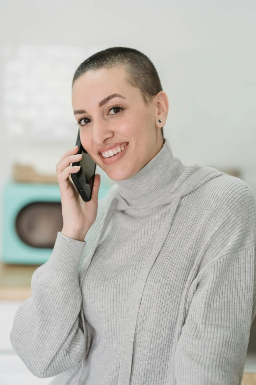 a woman talking on a cell phone in a kitchen, a picture, brown buzzcut, wearing turtleneck, promo image, caucasian