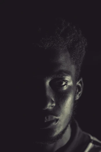 a black and white photo of a young man, by Maxwell Bates, pexels contest winner, realism, ( ( dark skin ) ), black tendrils, lit from bottom, soft shadow