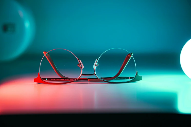 a pair of glasses sitting on top of a table, a digital rendering, pexels, teal silver red, blue rim light, close-up shoot, bright rim light