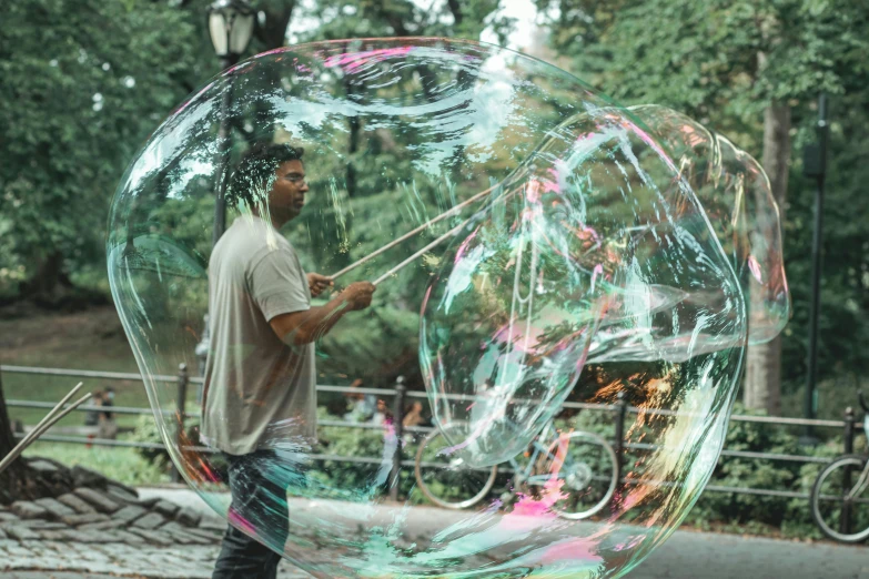 a man is playing with a giant bubble, inspired by Gordon Parks, pexels contest winner, central park, 🚿🗝📝, music album art, multi chromatic