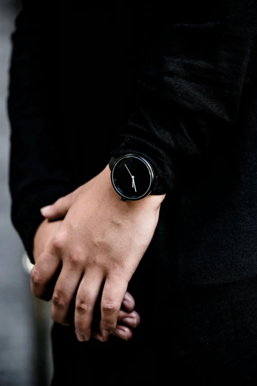 a close up of a person wearing a watch, inspired by Matija Jama, unsplash, black outfit, concrete, vantablack wall, standout colours