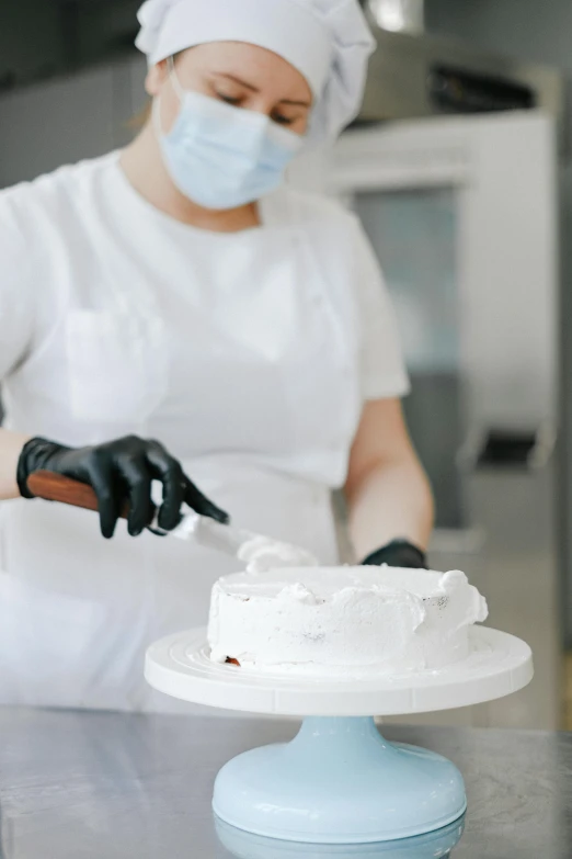 a woman in a face mask cutting a cake, a marble sculpture, trending on pexels, with a lab coat, white gloves, matte surface, prosthetics