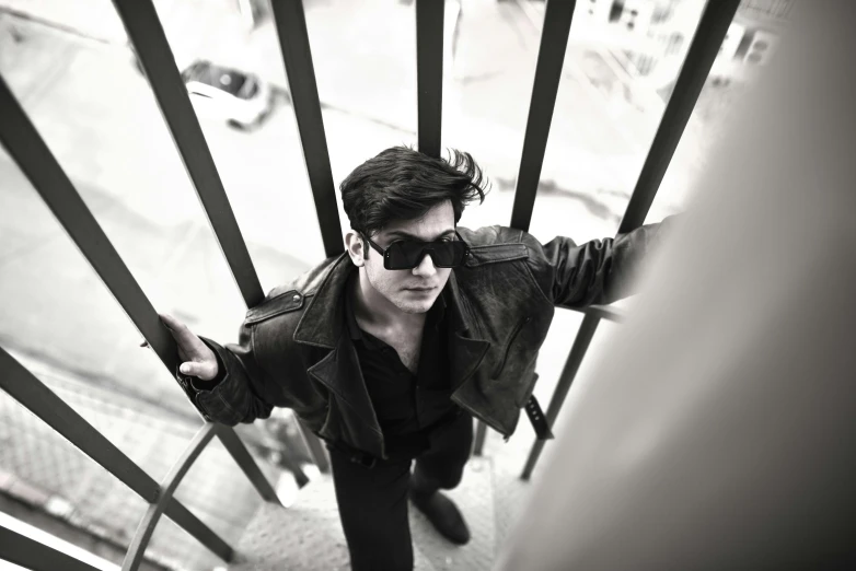 a man standing at the top of a set of stairs, an album cover, pexels contest winner, bauhaus, dressed in black leather, sayem reza, with sunglass, a handsome