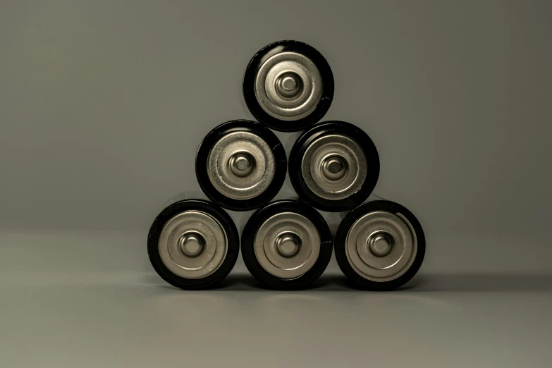 a stack of metal wheels sitting on top of each other, unsplash, digital art, massive battery, plain background, taken with canon eos 5 d, pyramid