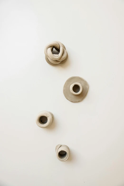 a white bowl sitting on top of a white counter, an abstract sculpture, by Rebecca Horn, unsplash, made of clay, rings, wall, installation