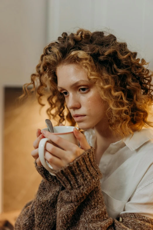 a woman with curly hair holding a cup of coffee, by Adam Marczyński, trending on pexels, renaissance, portrait of depressed teen, brown sweater, curly blonde hair | d & d, serious focussed look
