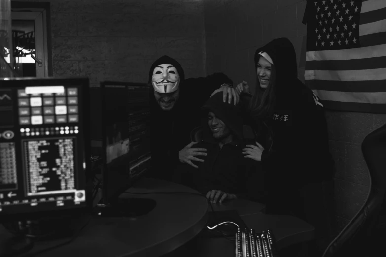 a group of people sitting in front of a computer, a black and white photo, unsplash, sots art, wearing a dark hood, the purge, creepy pose, anonymous mask