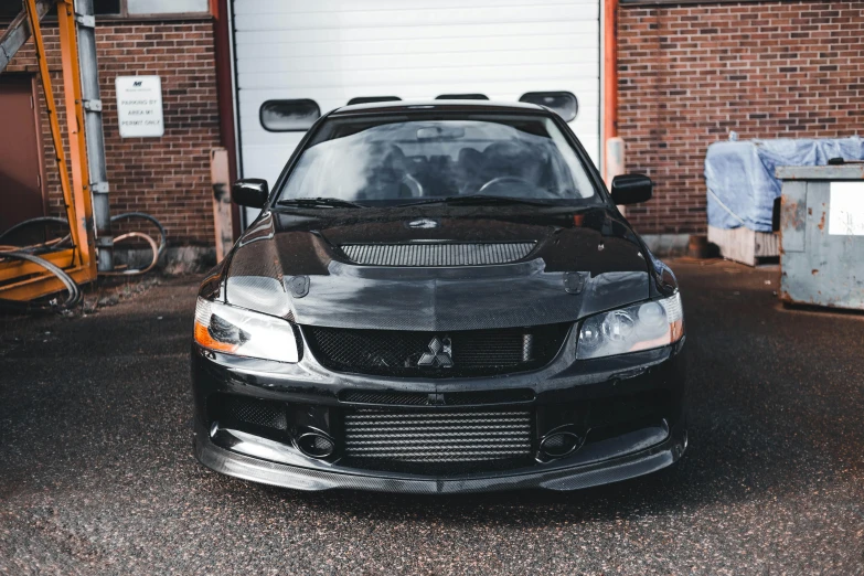 a black car parked in front of a garage, unsplash, japanese drift car, front view 2 0 0 0, with a white muzzle, 2000s photo