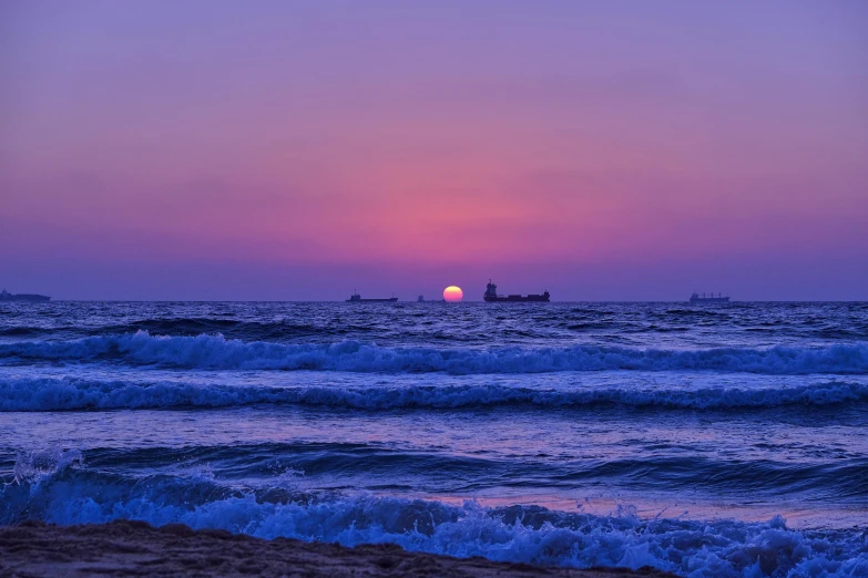 the sun is setting over the ocean on the beach, by Niko Henrichon, pexels contest winner, purple water, ships, vaporwave ocean, uncropped