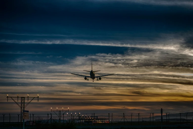 a large jetliner flying through a cloudy sky, pexels contest winner, evening lights, landing gear, thumbnail, runway