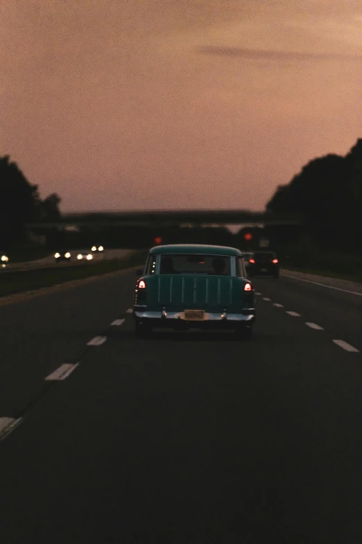 a car that is sitting on the side of the road, an album cover, unsplash, in the evening, vintage footage, americana, teal aesthetic