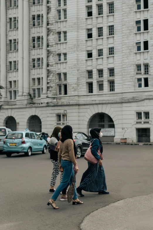 a group of people crossing a street in front of a building, inspired by Cheng Jiasui, trending on unsplash, quito school, asian women, background image, guwahati, with stalinist style highrise