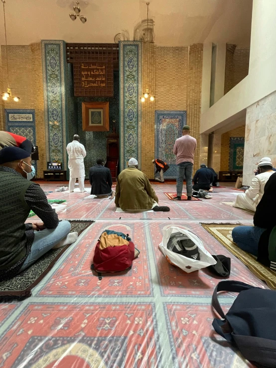 a group of people sitting on the floor of a building, mosque, thumbnail, covid, profile image