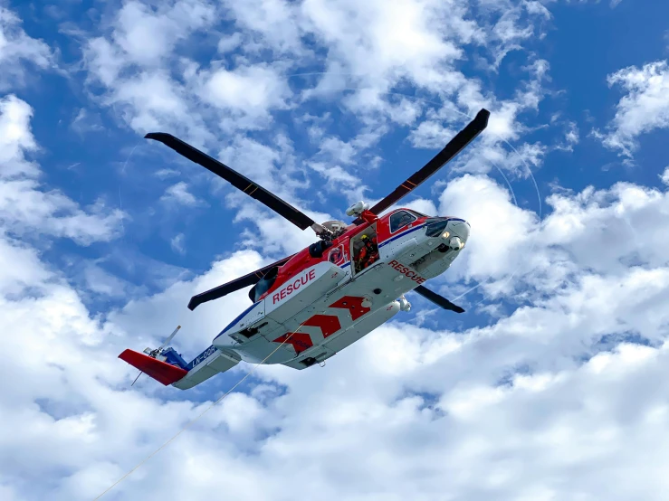 a red and white helicopter flying through a cloudy blue sky, by Carey Morris, pexels contest winner, flying emergency vehicles, avatar image, profile picture, sea king