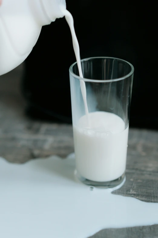 a person pouring milk into a glass on a table, no - text no - logo, calf, uncrop, soft