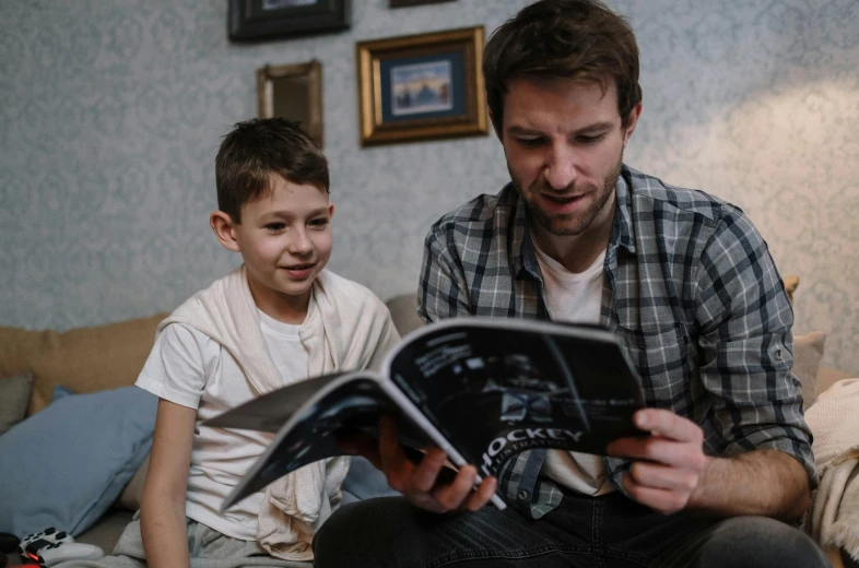 a man reading a book to a young boy, a picture, by Adam Marczyński, pexels contest winner, looking towards camera, avatar image, casual game, bowater charlie and brom gerald