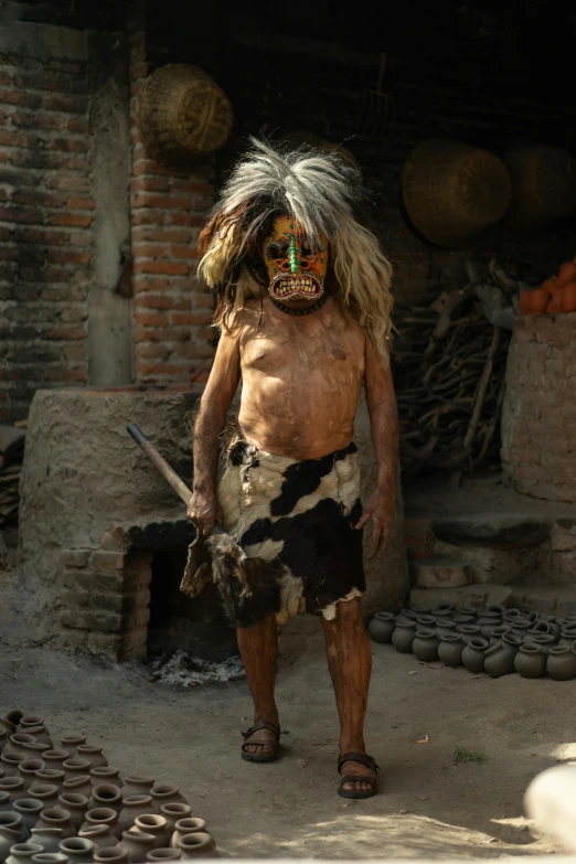a man that is standing in the dirt, an album cover, by Jan Tengnagel, pexels contest winner, sumatraism, ornate mask and fabrics, loin cloth, 5 years old, ancient blacksmith god