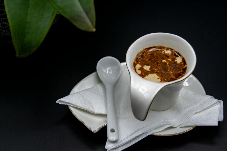 a cup of coffee sitting on top of a white plate, inspired by Ceferí Olivé, dau-al-set, spoon placed, daopao, detailed product image, maple syrup