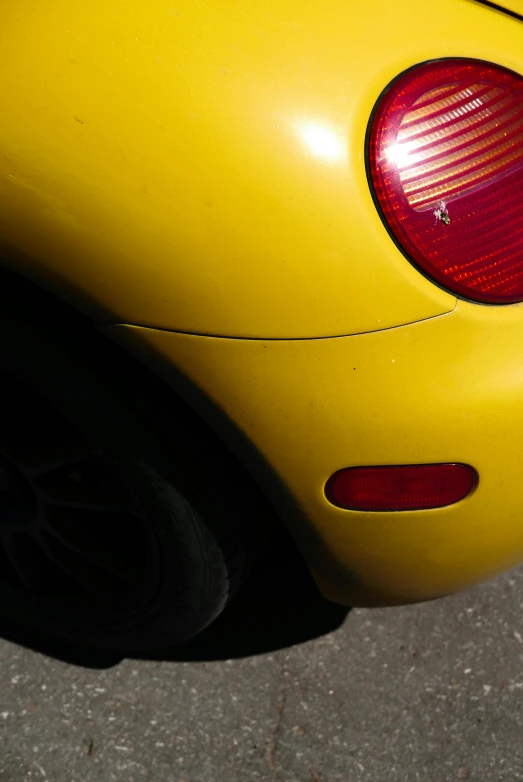 a close up of the rear end of a yellow car, by David Simpson, taken in the late 2000s, smooth oval head, slightly red, soft top