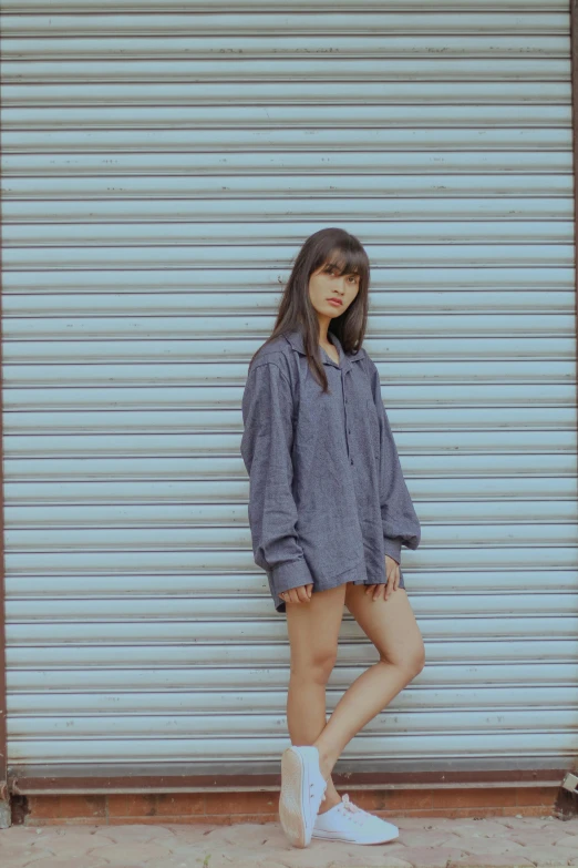 a woman standing in front of a garage door, an album cover, by Sengai, unsplash, realism, model エリサヘス s from acquamodels, button - up shirt, blue gray, lalisa manobal