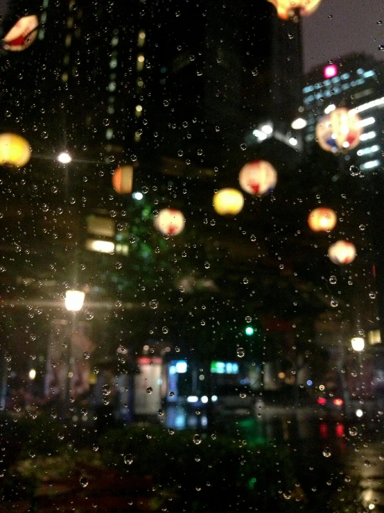 a view of a city at night through a rainy window, happening, chinese lanterns, hanging out with orbs, shinjuku, trending photo