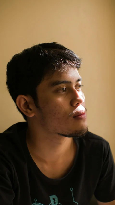 a man sitting at a table with a remote in his hand, an album cover, inspired by Jorge Jacinto, pexels contest winner, sumatraism, young man with beautiful face, ((portrait)), cleft chin, facing sideways