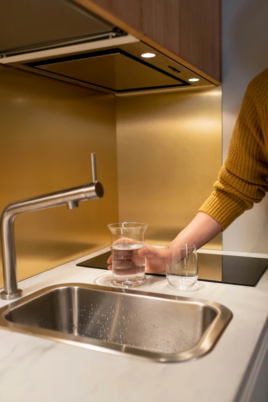 a woman washing her hands in a kitchen sink, a hologram, inspired by Albert Paris Gütersloh, gold and luxury materials, 4l, kitchenette and conferenceroom, stainless steel