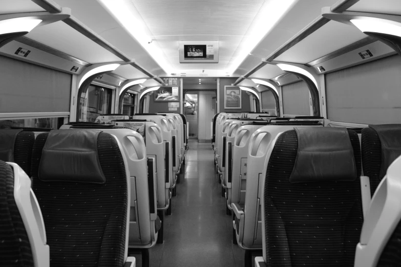 a black and white photo of the inside of a train, clean and empty, tourist photo, trending photo, sports photo