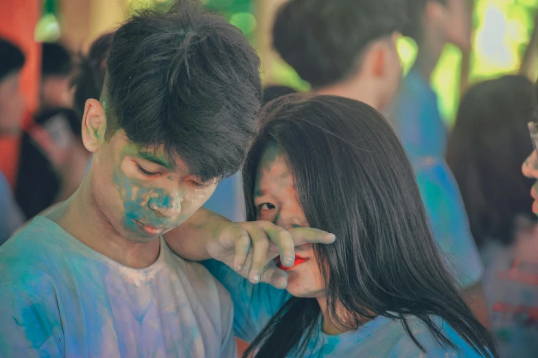 a couple of people standing next to each other, a colorized photo, pexels contest winner, synchromism, fully covered in colorful paint, hand on cheek, kids playing, blueish