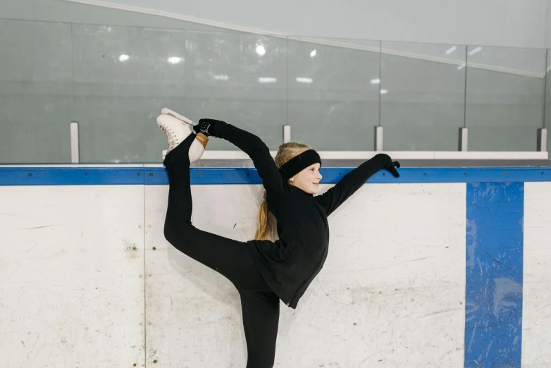 a woman doing a handstand on an ice rink, pexels contest winner, wearing skating helmet, kids, looking left, black