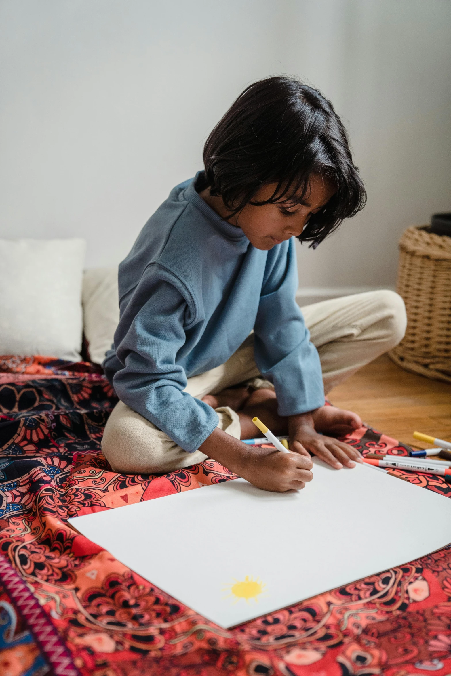 a little girl sitting on the floor drawing on a piece of paper, pexels contest winner, visual art, faridah malik, young boy, indigenous art, studyng in bedroom