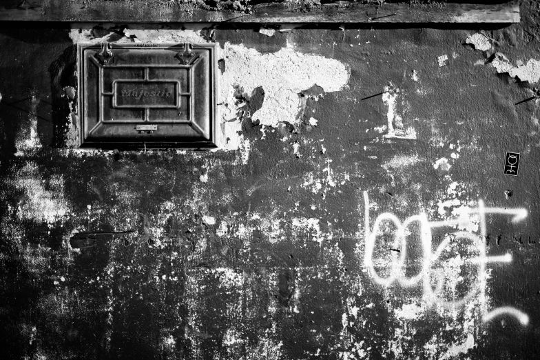 a black and white photo of graffiti on a wall, a black and white photo, by Luca Zontini, letterbox, weathered, lockbox, ::