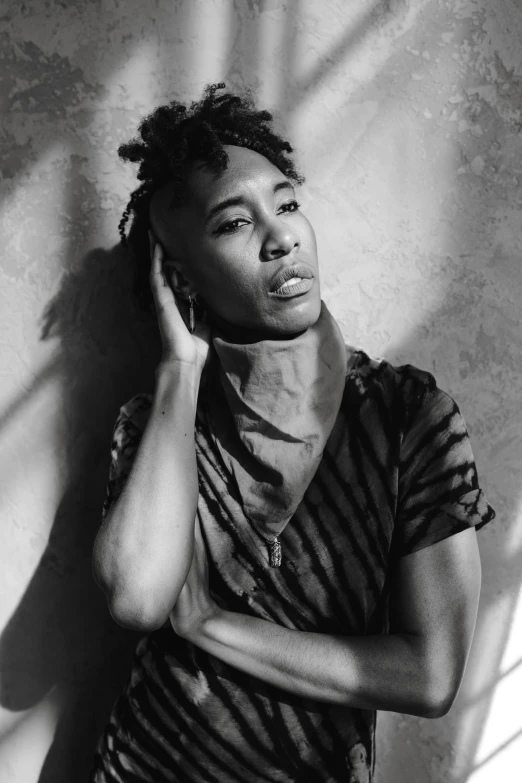 a black and white photo of a woman leaning against a wall, androgynous male, atiba jefferson, lit from above, complex background