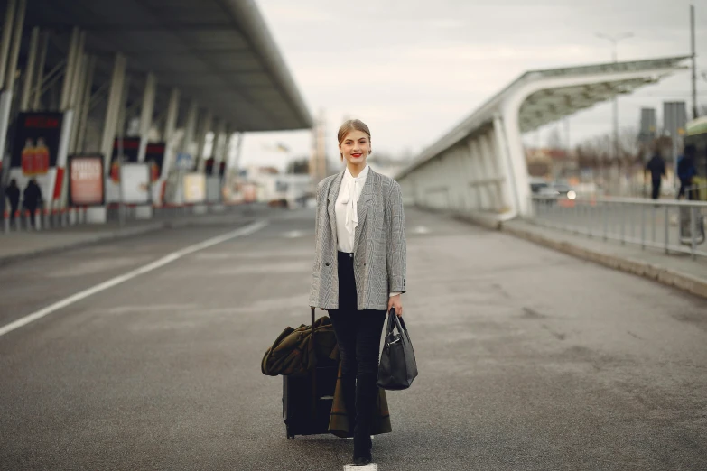 a woman is walking down the street with her luggage, pexels contest winner, wearing lab coat and a blouse, avatar image, black. airports, posing for camera